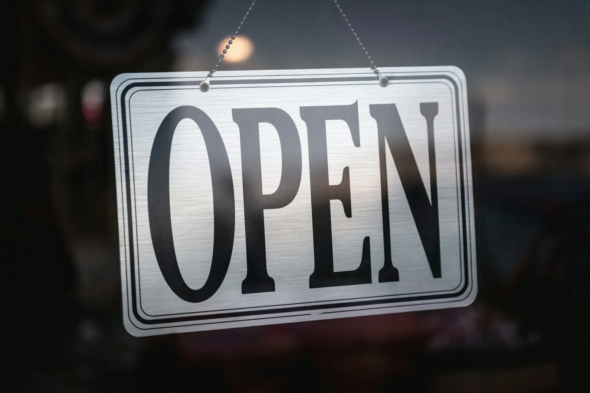 An OPEN sign hanging inside a shop window.