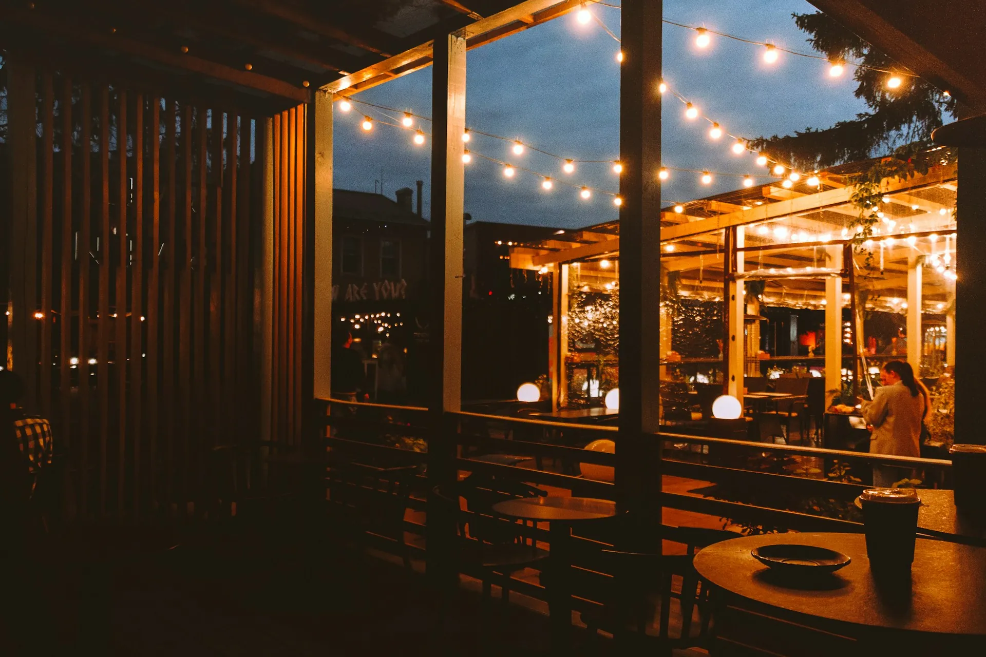 A business lit up at dusk with the lights on and tables out.