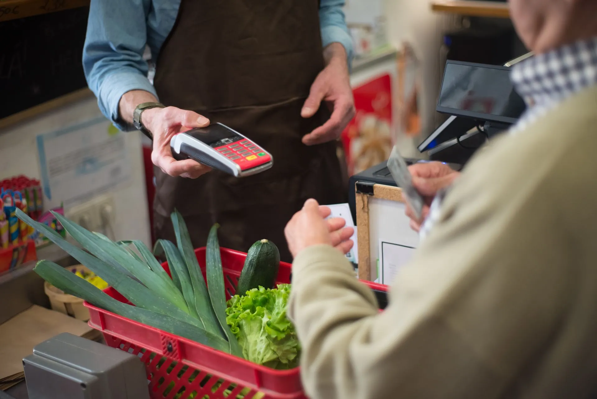 A shopper checking their phone while carrying a basket.